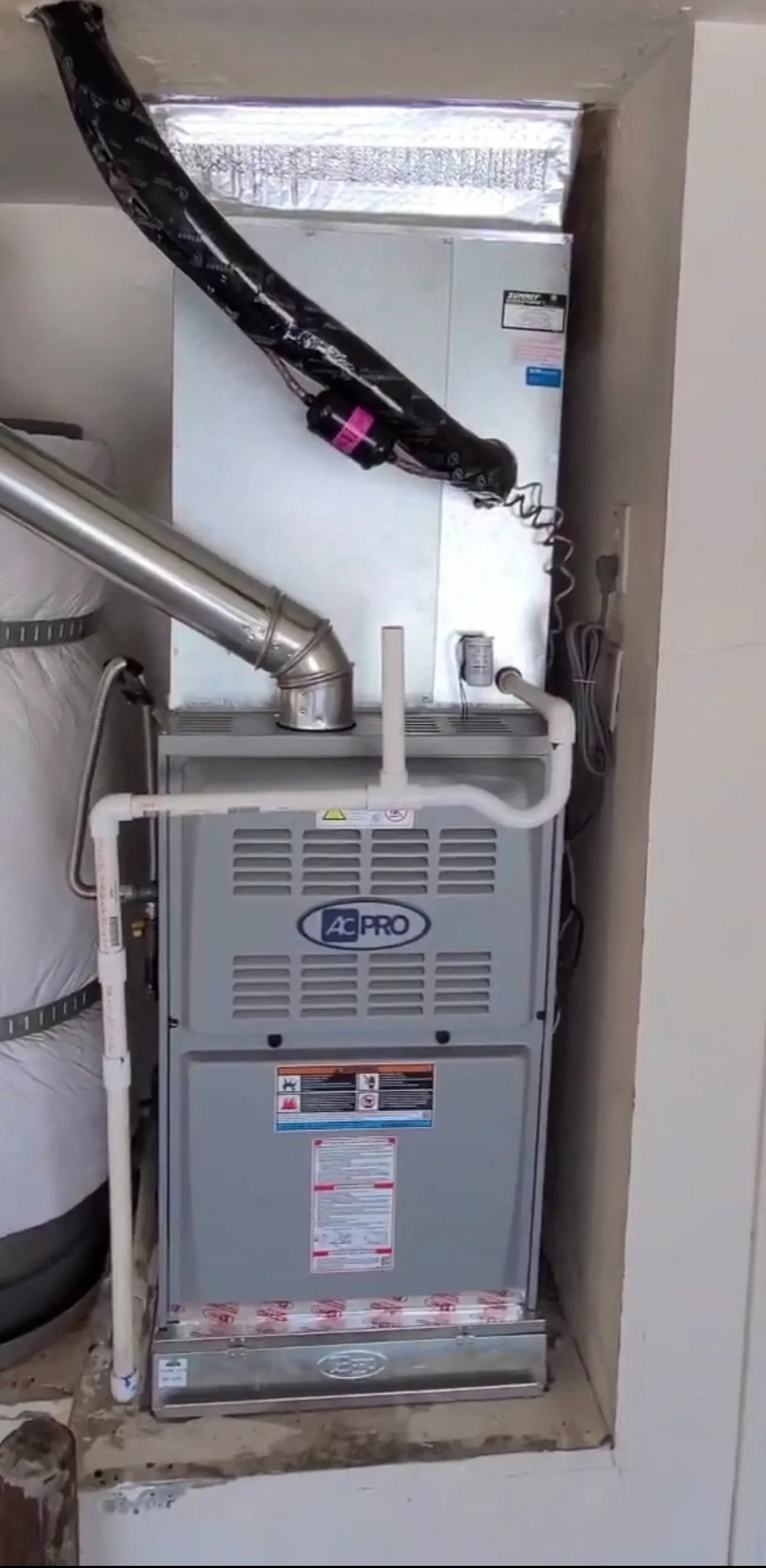 AC PRO furnace with white PVC piping and metal ductwork installation in utility closet